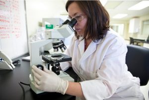 Young woman looking through a microscope, doing essential oils research. Have you discovered essential oils yet?